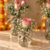 Small round glass jar with a single pink-edged rose, baby's breath and jute bow, close-up
