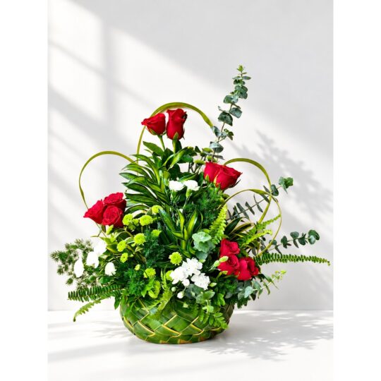 Red rose centrepiece in Bangalore with white spray carnations, green button chrysanthemums and eucalyptus in a handwoven coconut leaf basket