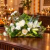 White oriental lily and chrysanthemum arrangement in a coconut leaf base on a console, angled view