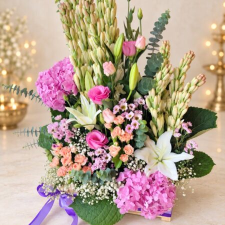 Fragrant exotic flower arrangement in a wooden crate with purple ribbon, front view