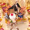 Wooden crate Diwali hamper with urli candle, gold lanterns, popcorn tin and chocolates, front view