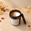 Amber glass candle jar opened to show the cream plant-based wax and wick, angled view
