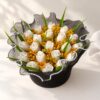 White tulip candles with mustard baby's breath inside a pearl-edged black net collar, top view