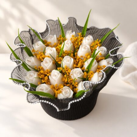 White tulip candles with mustard baby's breath inside a pearl-edged black net collar, top view