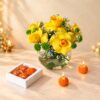 Yellow rose and button chrysanthemum vase with laddoo candles lit, angled view