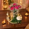 Dark pink carnation and baby’s breath centrepiece on a round mirror base, top angled view