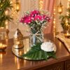 Carnation and baby’s breath centrepiece with gold metal lantern and rose candle on a mirror base, side view
