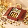 Open jharokha gift box with salted pistachio and cashew jars and a tray of 9 Ferrero Rocher, angled view