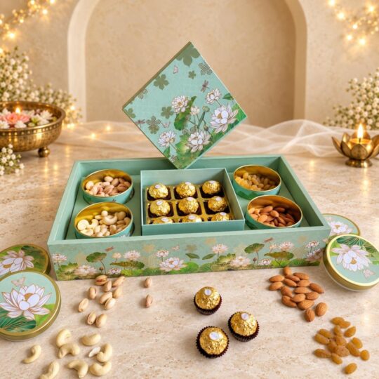 Open mint and gold lotus-print gift box with round tins of pistachios, cashews, almonds and raisins around a tray of Ferrero Rocher, angled view