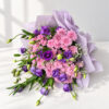 Lisianthus and pink chrysanthemum bouquet in lilac wrap lying flat, angled view