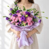 Purple lisianthus and pink chrysanthemum bouquet held in hands, front view