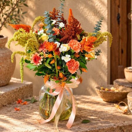 Ronda Sunset orange flower arrangement in Bangalore with carnations, celosia and trailing amaranthus in a glass jar vase