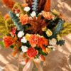 Sunset-coloured flower arrangement in a glass jar vase with ribbon, top view