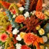 Close-up of peach carnations, yellow spray roses, white spray carnations and orange celosia with amaranthus