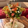 Orange, peach and white flower arrangement with eucalyptus and amaranthus plumes in a glass jar vase, front view