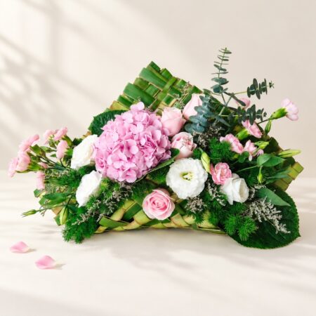 Pink hydrangea centrepiece in Bangalore with pink roses, spray carnations, white eustoma and eucalyptus on a handwoven coconut leaf base
