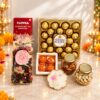 Contents of the Diwali hamper with Ferrero Rocher, Loyka almond brittle, potpourri, laddoo candles, urli diya candle, almonds and cashews