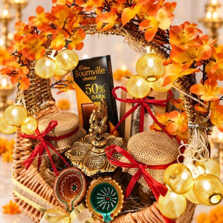 Panch diya, clay diyas and dry fruit jars in a cane Diwali hamper with gold fairy lights, close front view