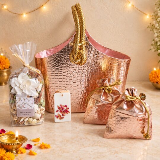 Rose gold gift bag with potpourri, wax sachet and drawstring dry fruit potlis, angled view