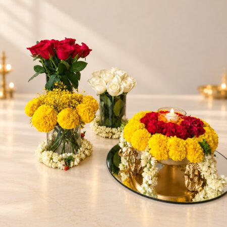 Diwali flower decoration set in Bangalore with red rose, white rose and marigold vases, mogra collars and an elephant urli on a mirror